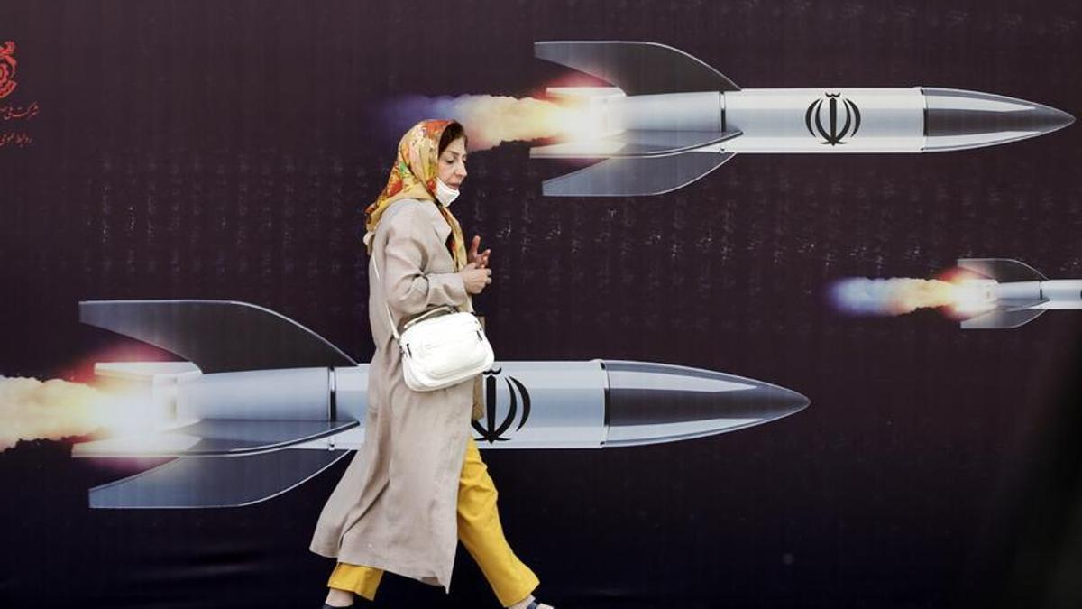 Una mujer iraní pasa junto a un gran anuncio anti-israelí con imágenes de misiles en Teherán.