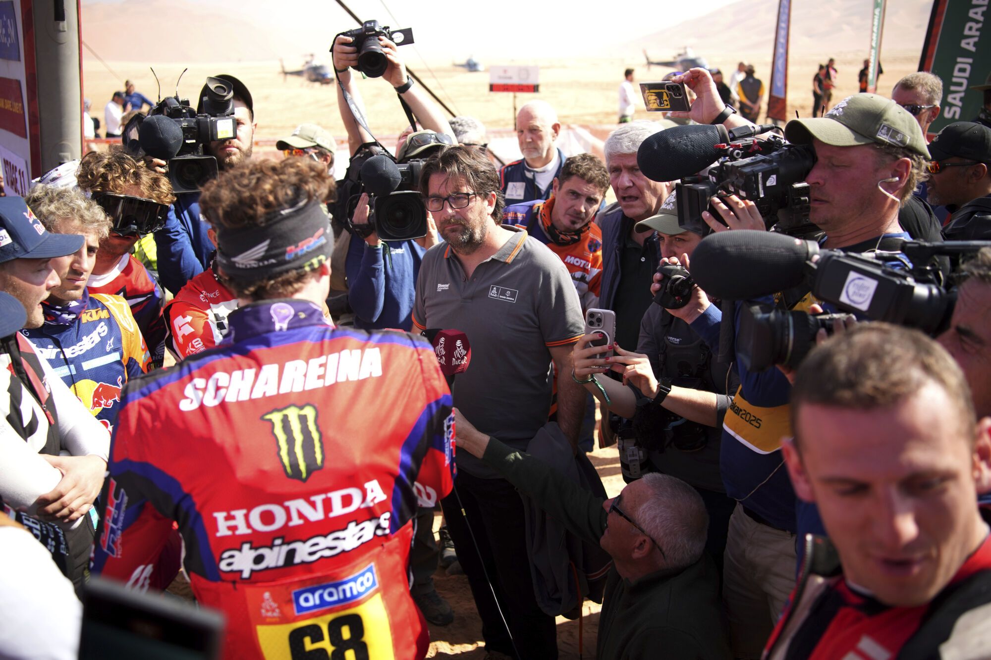 Race director David Castera, center, speaks with riders at the start delayed due to fog during the eleventh stage of the Dakar Rally with start and finish in Shubaytah, Saudi Arabia, Thursday, Jan. 16, 2025. (AP Photo/Christophe Ena)