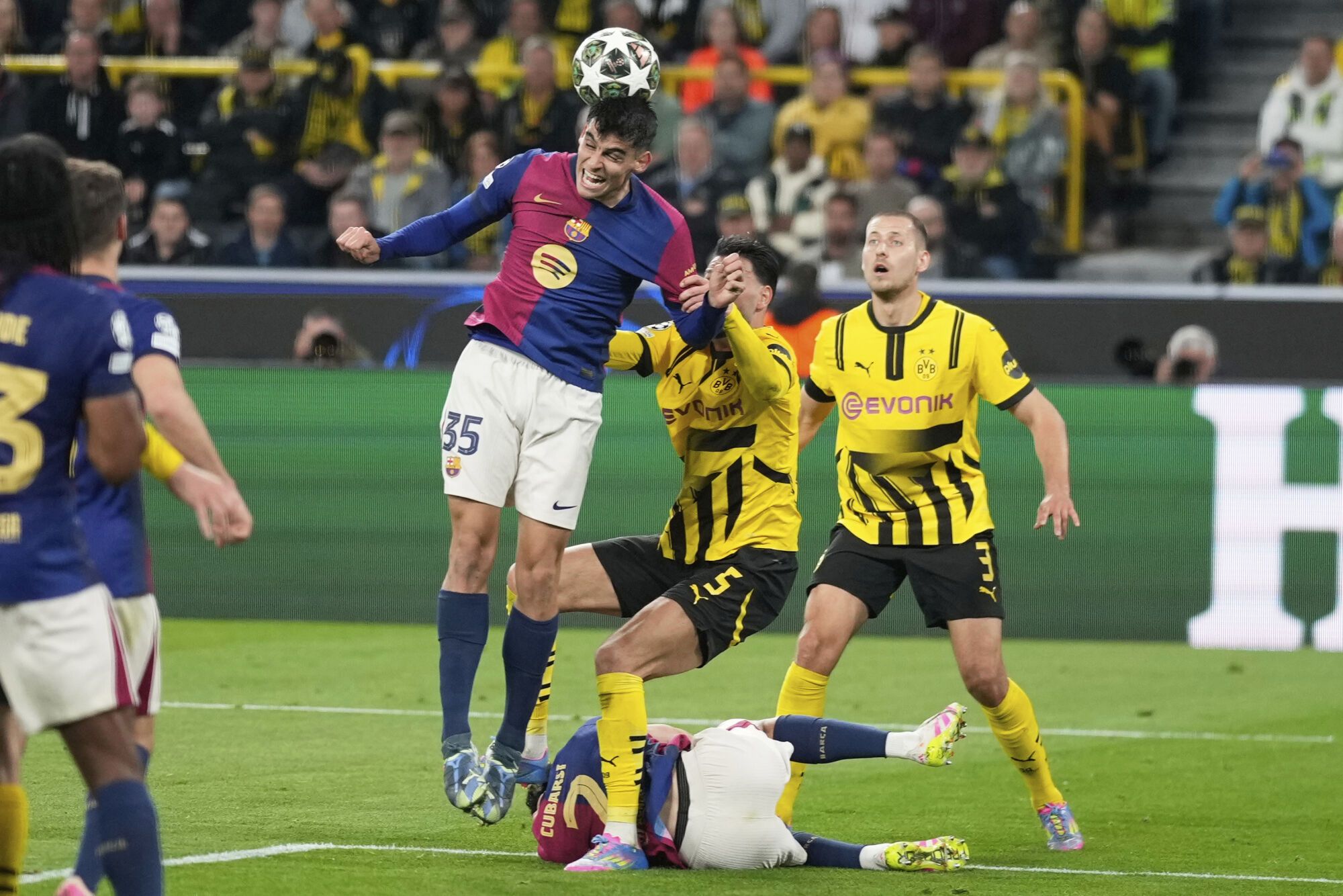 Barcelona's Gerard Martin, top, clears the ball past Dortmund's Ramy Bensebaini (5) during the Champions League quarterfinals second leg soccer match between Borussia Dortmund and Barcelona, at the Signa-Iduna Park in Dortmund, Germany, Tuesday, April 15, 2025. (AP Photo/Matthias Schrader)