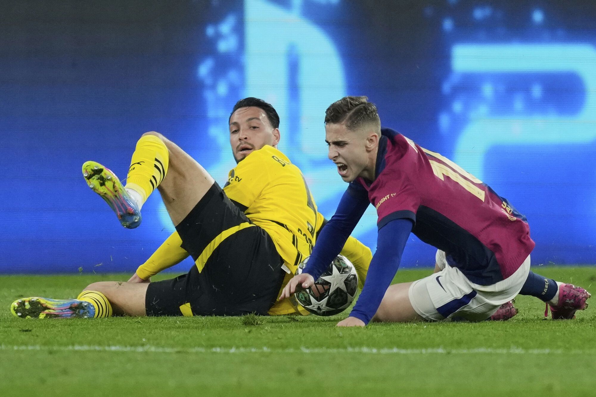 Barcelona's Fermin Lopez, right, duels for the ball with Dortmund's Ramy Bensebaini during the Champions League quarterfinals second leg soccer match between Borussia Dortmund and Barcelona, at the Signa-Iduna Park in Dortmund, Germany, Tuesday, April 15, 2025. (AP Photo/Martin Meissner)