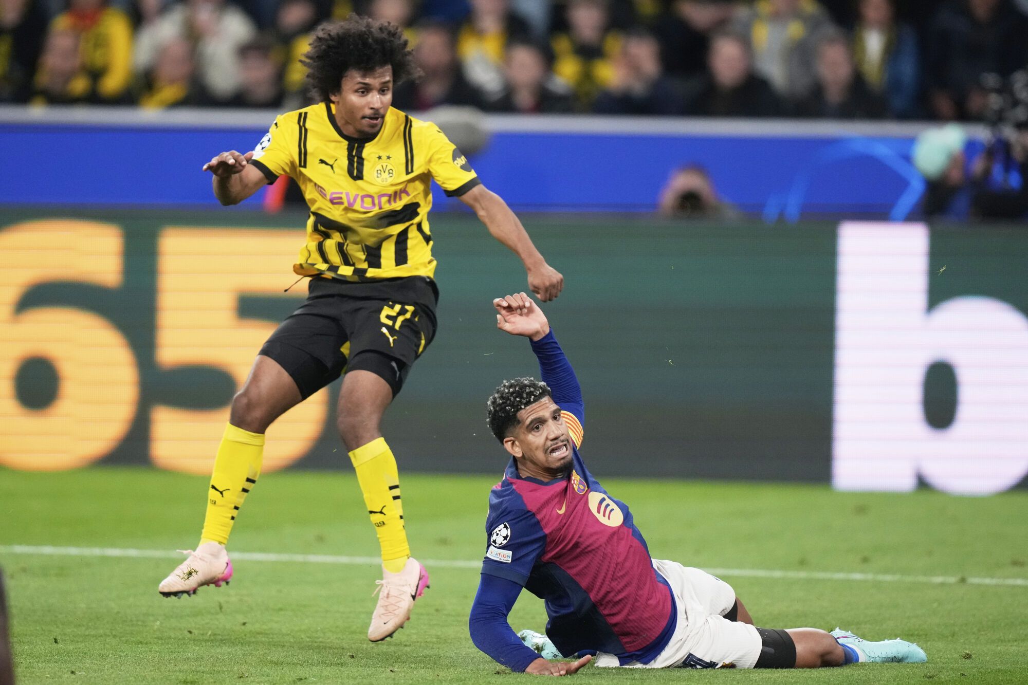 Barcelona's Ronald Araujo, bottom, tries block a shot by Dortmund's Karim Adeyemi during the Champions League quarterfinals second leg soccer match between Borussia Dortmund and Barcelona, at the Signa-Iduna Park in Dortmund, Germany, Tuesday, April 15, 2025. (AP Photo/Matthias Schrader)