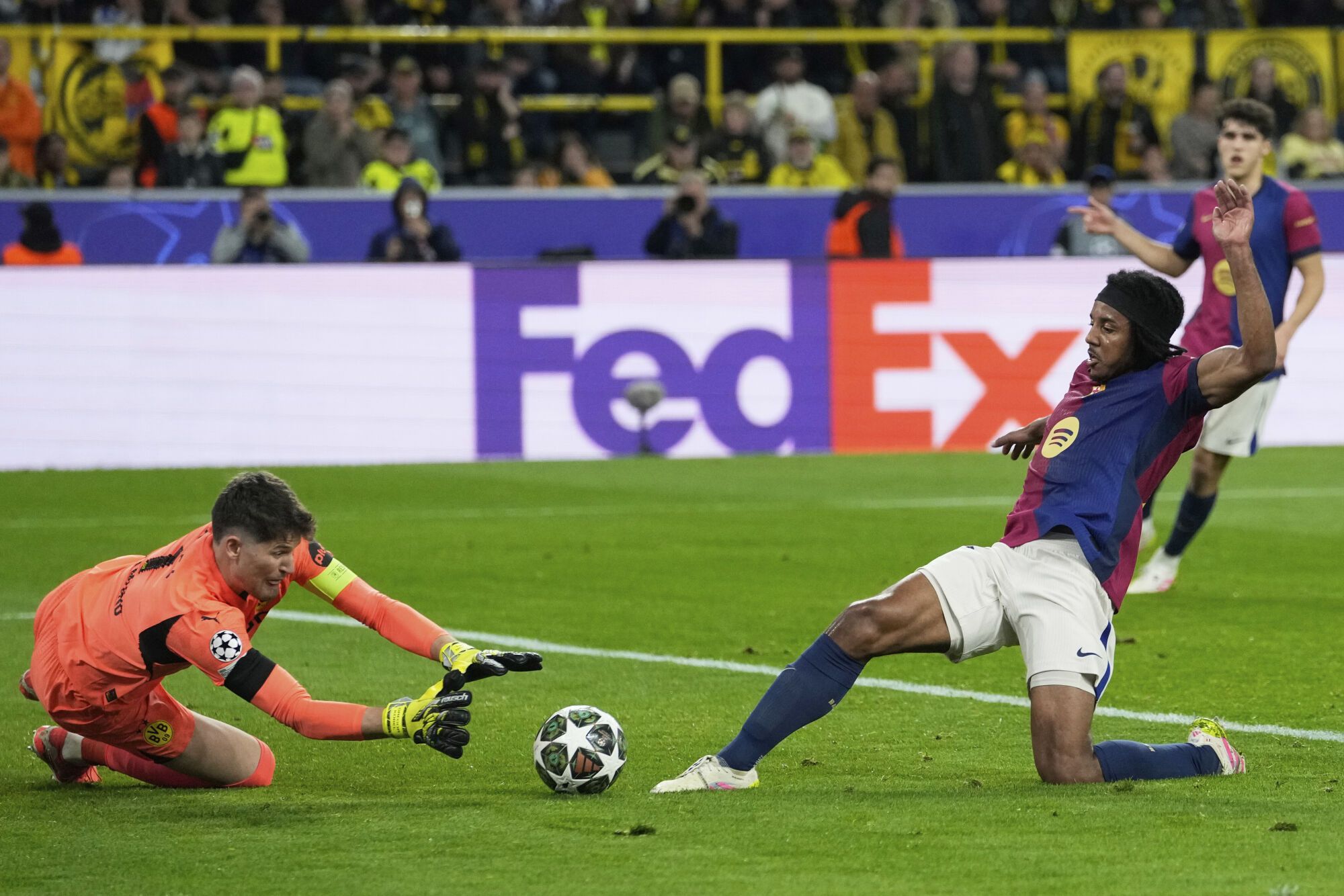 Dortmund's goalkeeper Gregor Kobel, left, makes a save in front of Barcelona's Jules Kounde during the Champions League quarterfinals second leg soccer match between Borussia Dortmund and Barcelona, at the Signa-Iduna Park in Dortmund, Germany, Tuesday, April 15, 2025. (AP Photo/Martin Meissner)