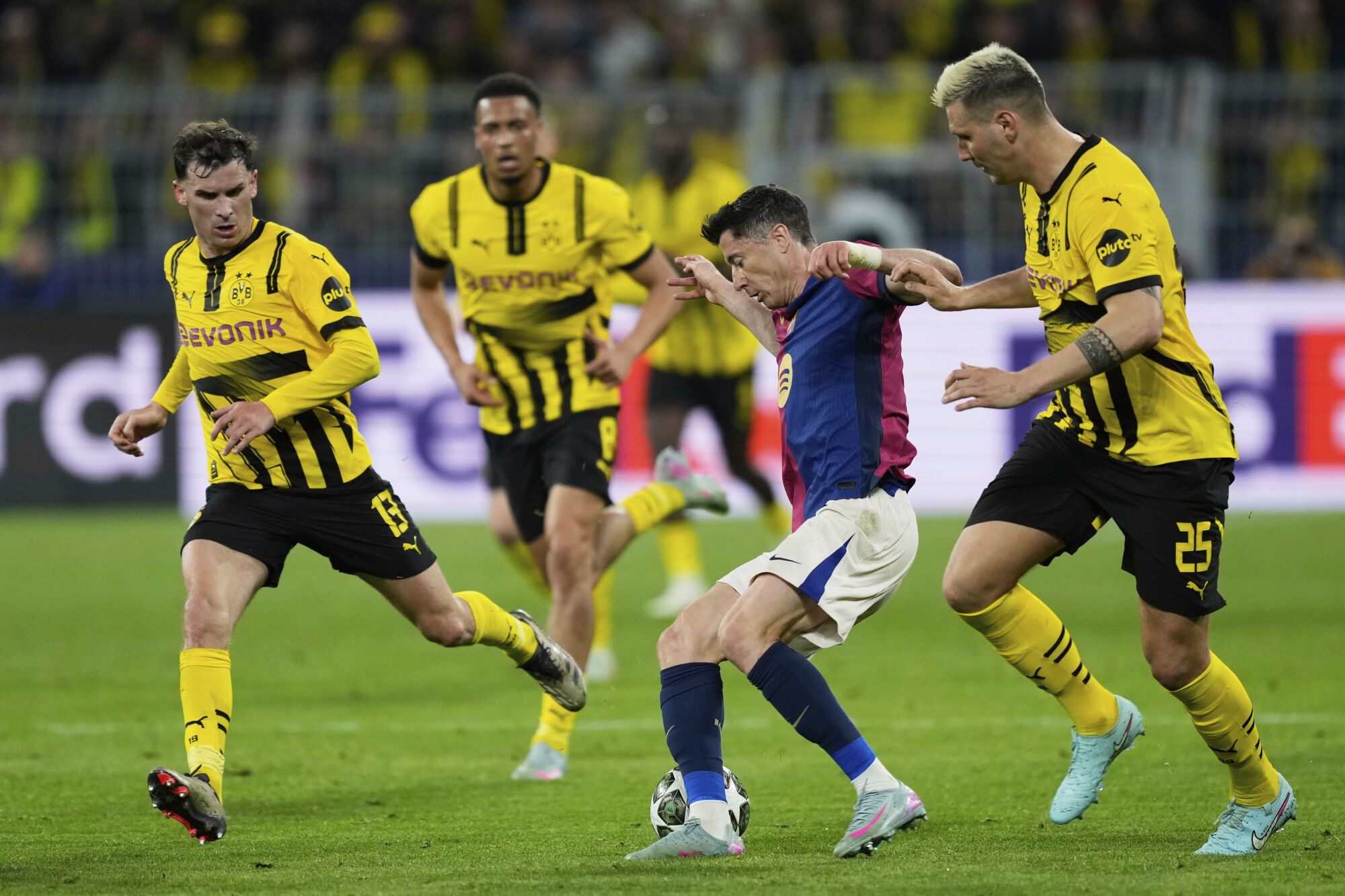 Barcelona's Robert Lewandowski, second right, duels for the ball with Dortmund's Niklas Suele, right, during the Champions League quarterfinals second leg soccer match between Borussia Dortmund and Barcelona, at the Signa-Iduna Park in Dortmund, Germany, Tuesday, April 15, 2025. (AP Photo/Martin Meissner)