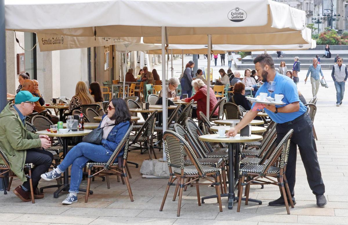 Un camarero limpiando la mesa de una terraza en un bar de Vigo.