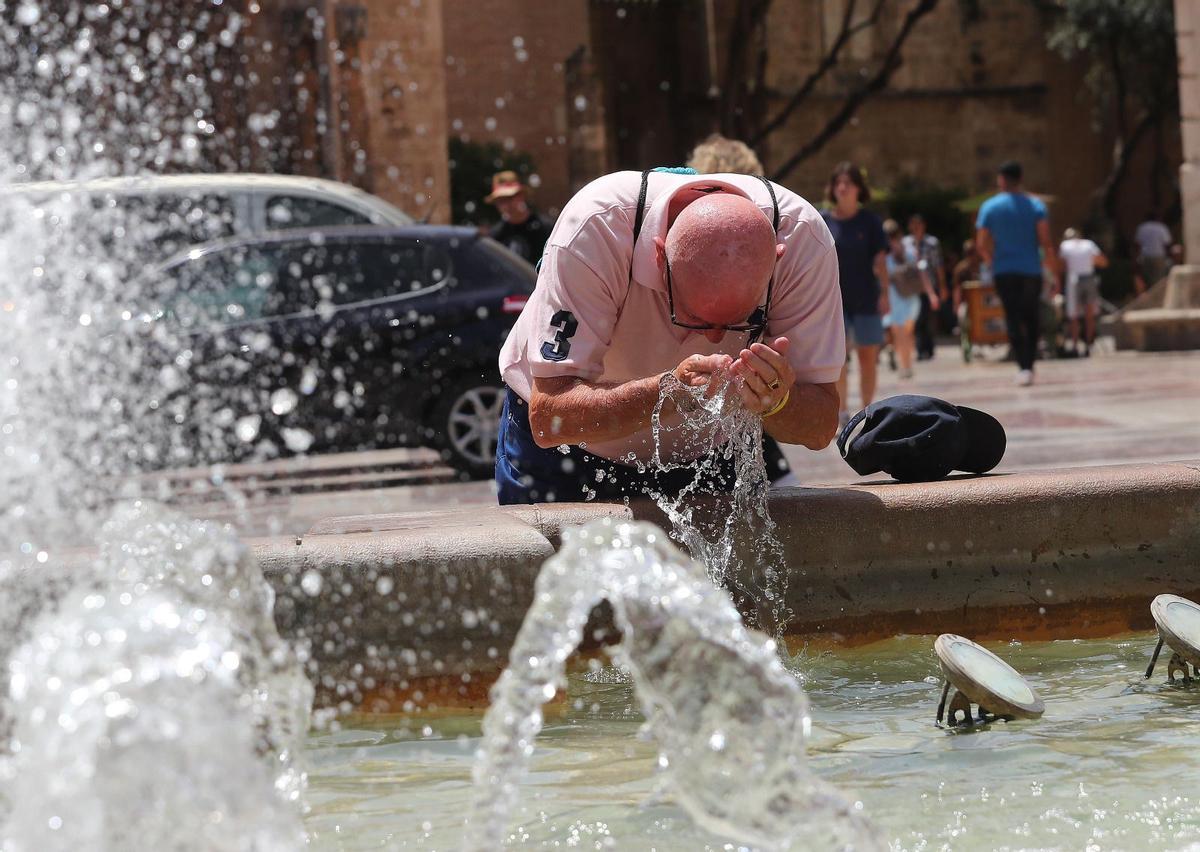 Hombre refrescándose en una fuente de Valencia